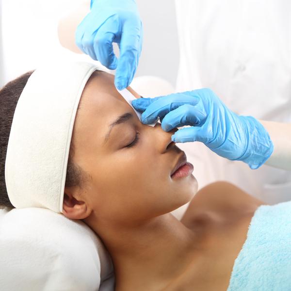 An African American woman receive a wax treatment from a licensed Esthetician in a salon